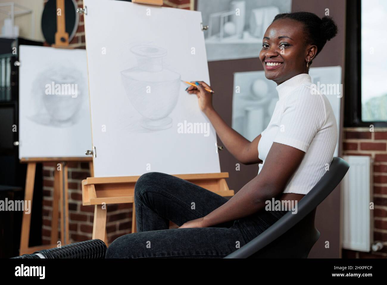 Portrait de l'étudiant souriant et dessin croquis sur toile pendant la classe d'art créatif. Jeune femme profitant de la leçon d'art développer de nouvelles compétences artistiques en studio de créativité. Résolutions du nouvel an Banque D'Images