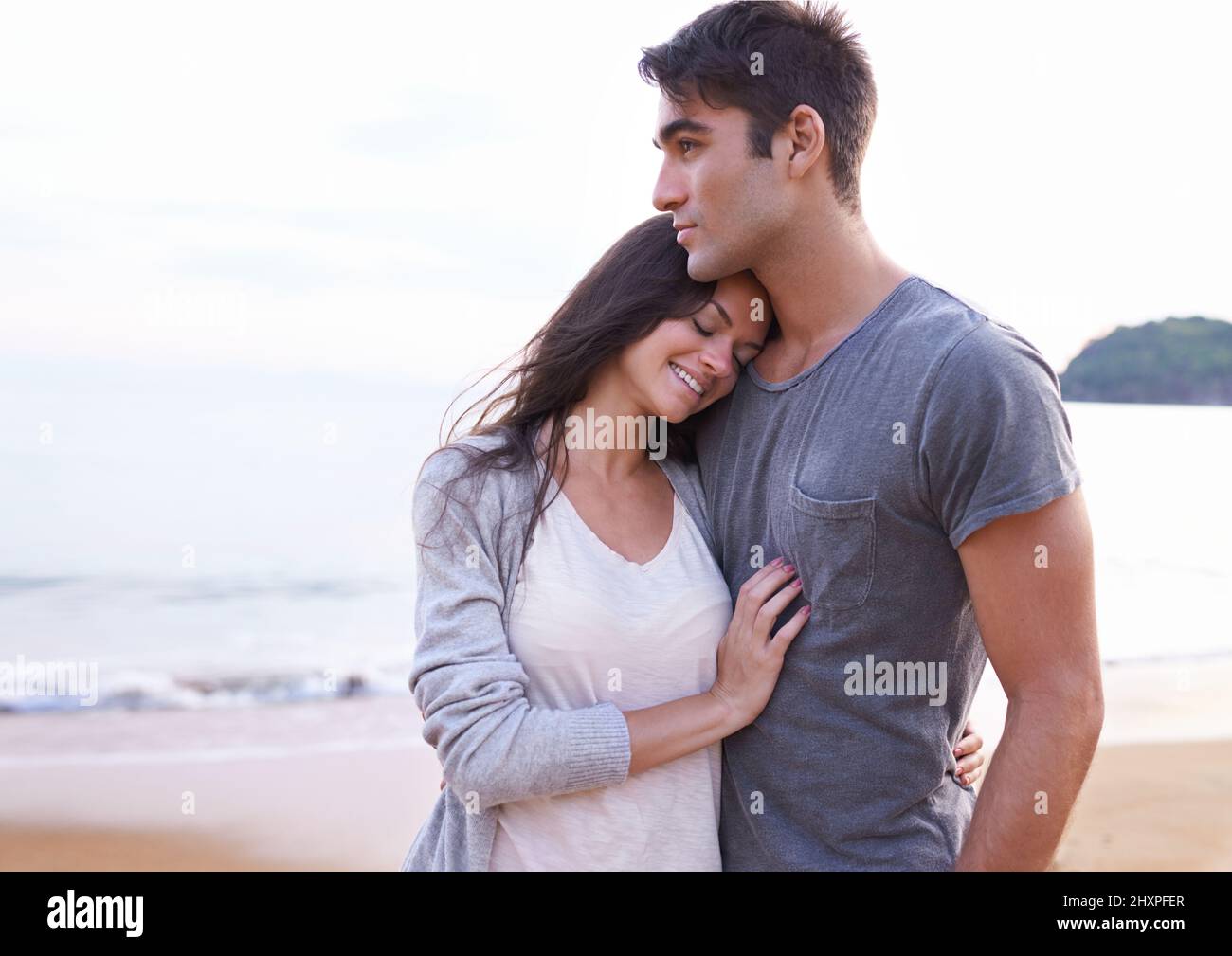 Mon endroit préféré est à côté de vous. Photo courte d'un jeune couple affectueux à la plage. Banque D'Images
