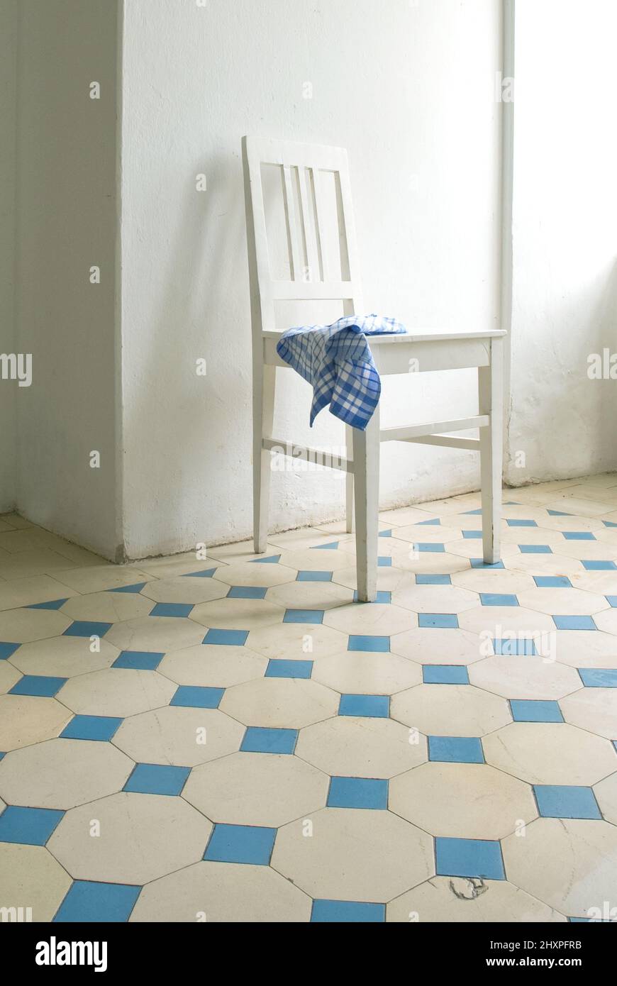 chaise de cuisine blanche avec torchon bleu et blanc sur carrelage blanc et bleu Banque D'Images
