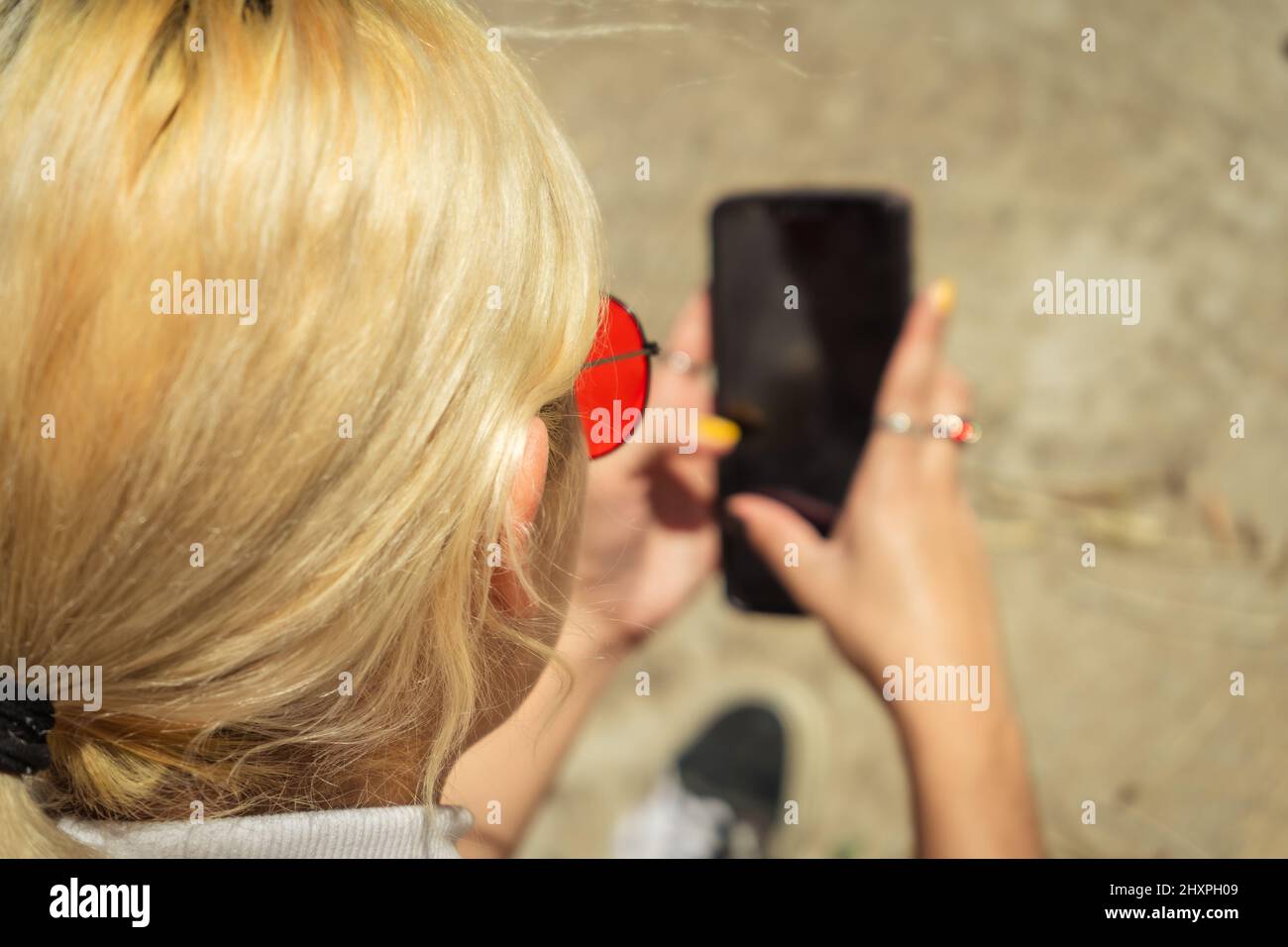 Une jeune femme vérifie son téléphone portable par beau temps. Vue aérienne. Concentrez-vous sur la femme. Banque D'Images