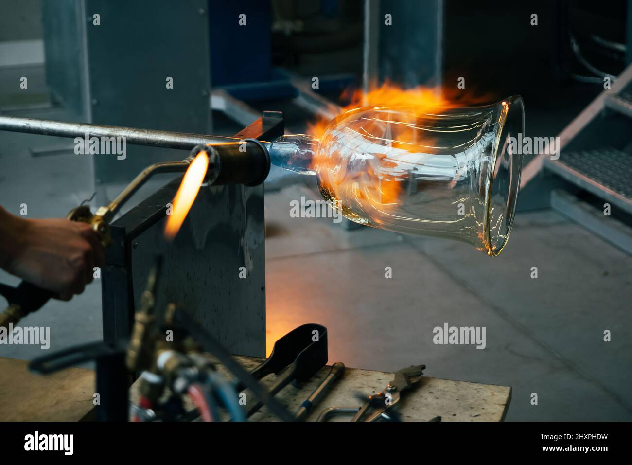 Gros plan d'un souffleur de verre artisan façonnant le verre chaud fondu au feu fort à l'intérieur d'un atelier. Traitement manuel du verre par les artisans à l'intérieur d'un gla Banque D'Images