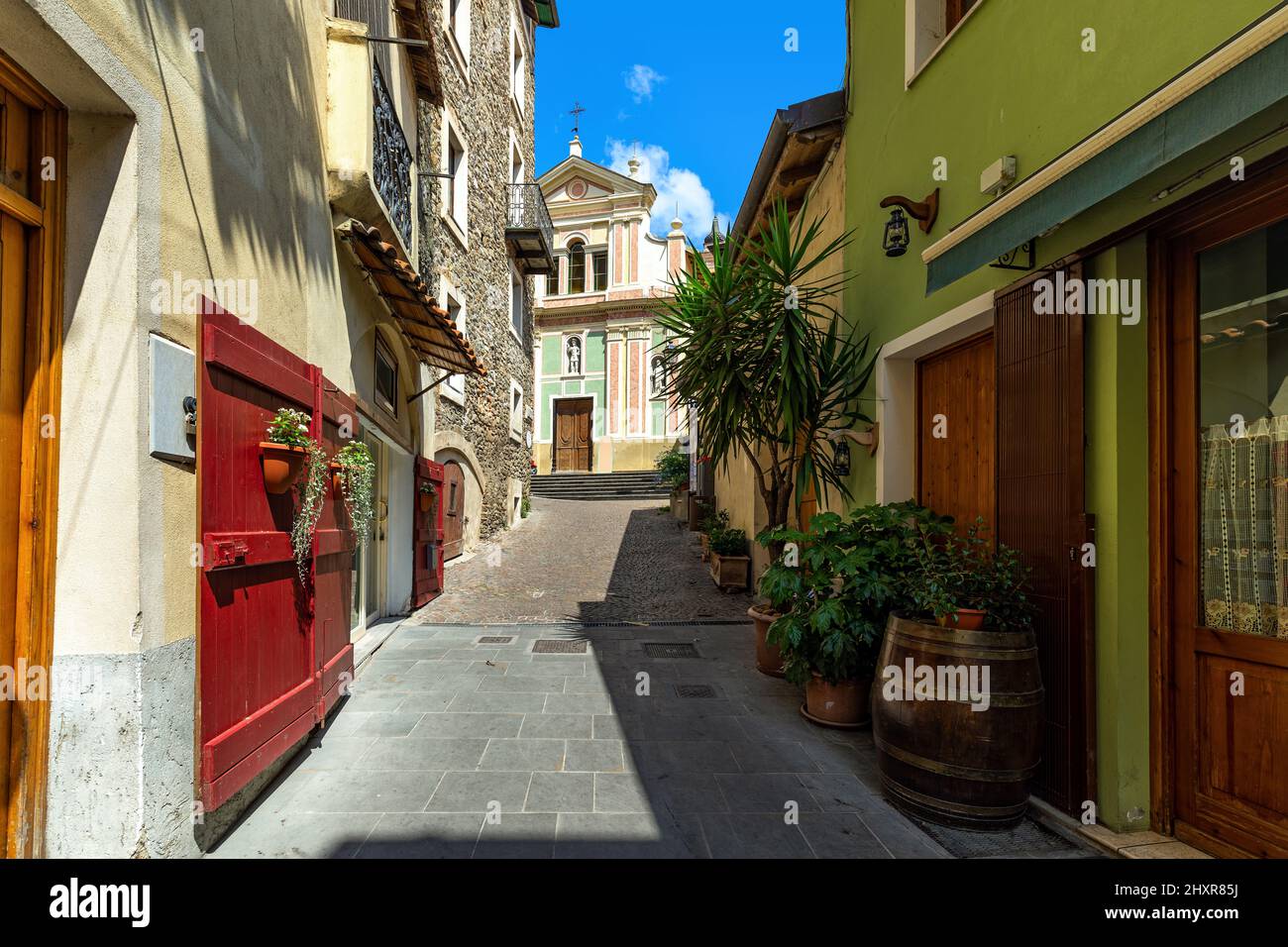 Rue étroite parmi les petites maisons comme église catholique sur fond dans la vieille ville de Dolceacqua, Ligurie, Italie. Banque D'Images