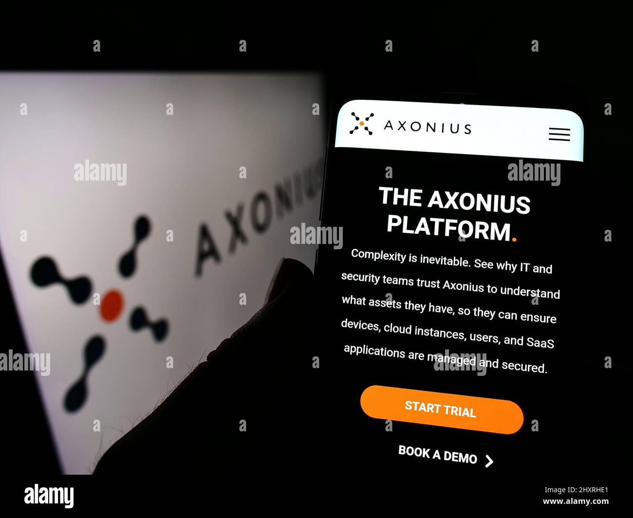 Personne tenant un téléphone portable avec la page Web de la société américaine de cybersécurité Axonius Inc. À l'écran devant le logo. Concentrez-vous sur le centre de l'écran du téléphone. Banque D'Images