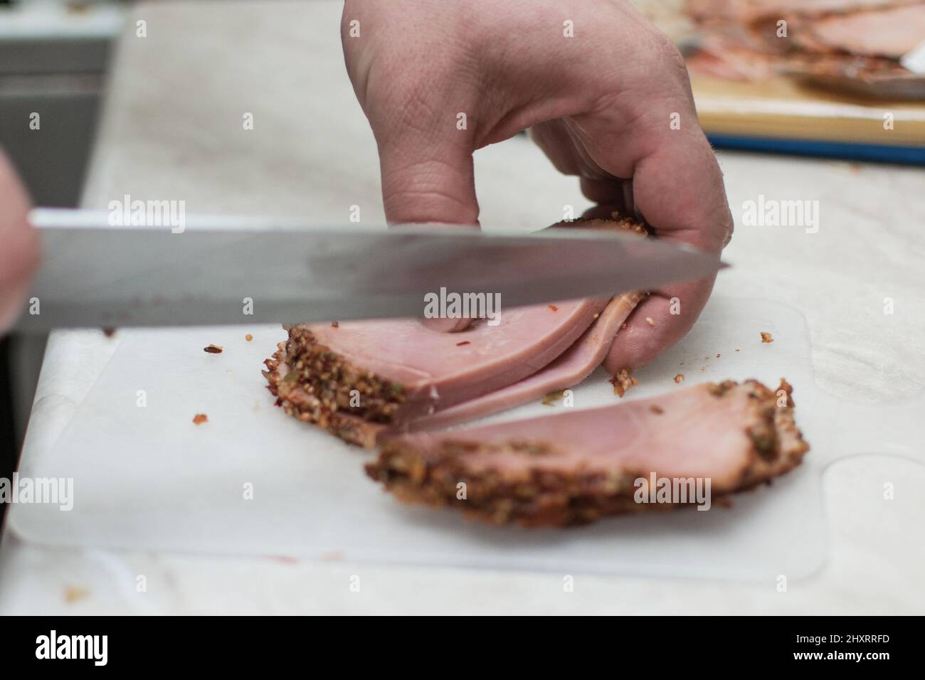 Des hommes ont coupé du jambon, préparé de la viande sur une planche à découper. Banque D'Images