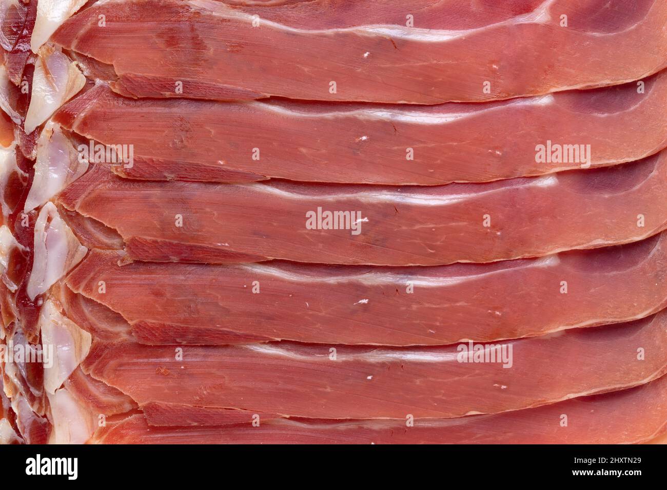 Émincé de jambon cru espagnol, jambon serrano, gros plan plein cadre comme arrière-plan Banque D'Images