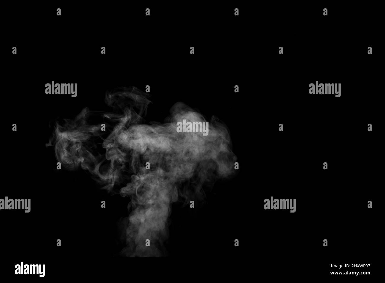 Vapeur blanche et bouclés qui s'élève isolée sur un fond noir. Évaporation de liquide et condensation. Peut être utilisé comme arrière-plan, élément de conception Banque D'Images