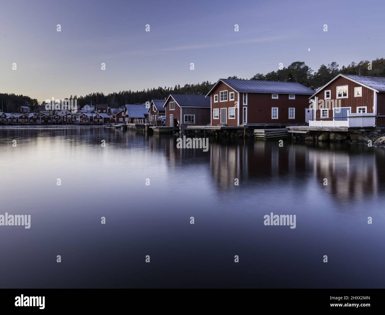 Belle vue de maisons rouges en bois près d'un lac avec réflexion dans l'eau à Bonhamn, Suède Banque D'Images
