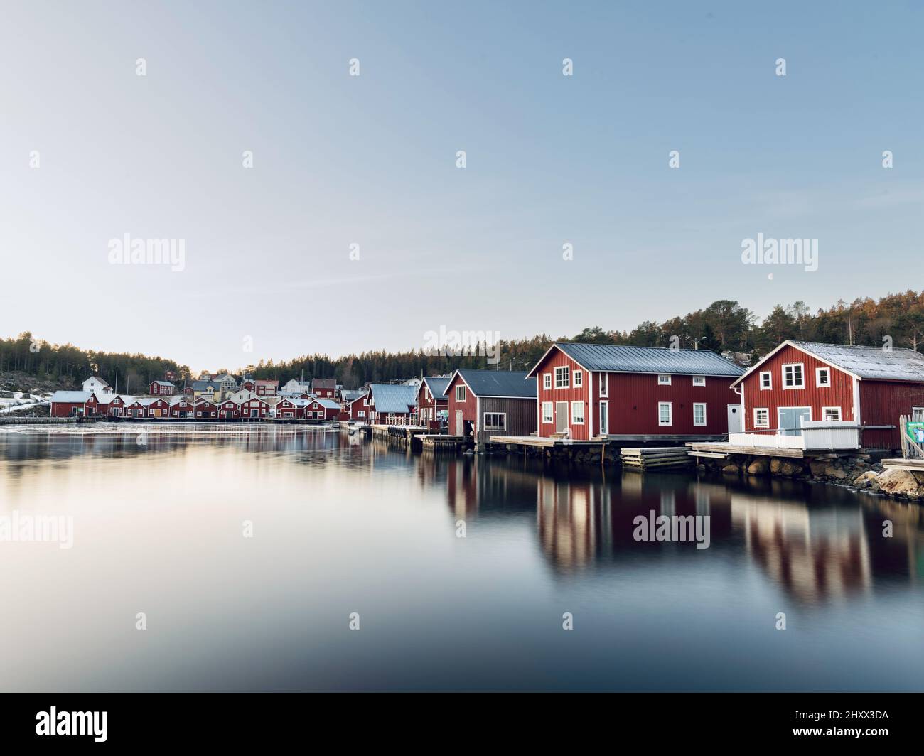 Belle vue de maisons rouges en bois près d'un lac avec réflexion dans l'eau à Bonhamn, Suède Banque D'Images