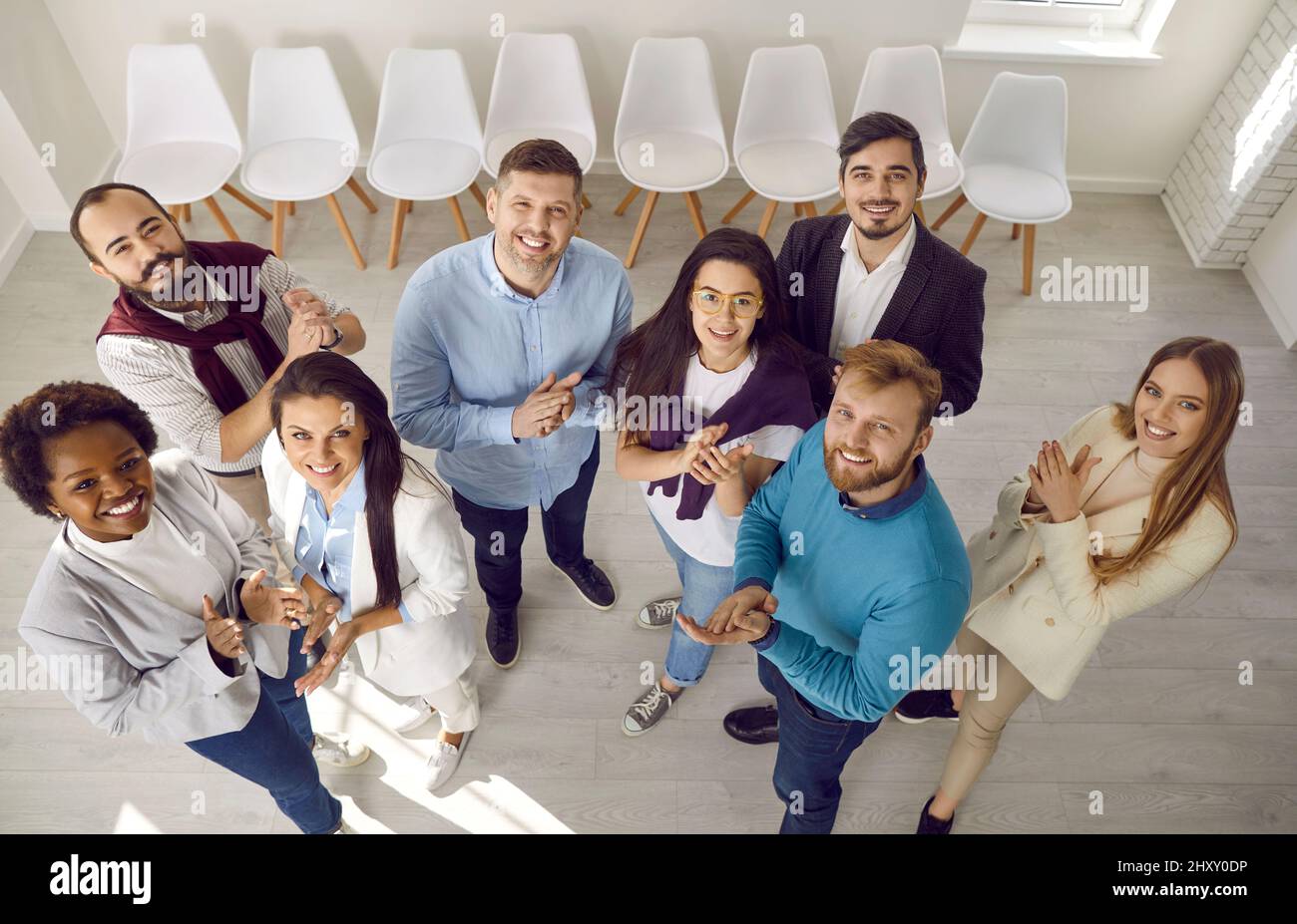 Une équipe diversifiée de gens d'affaires heureux se tenant ensemble, souriant et accrocetant les mains Banque D'Images