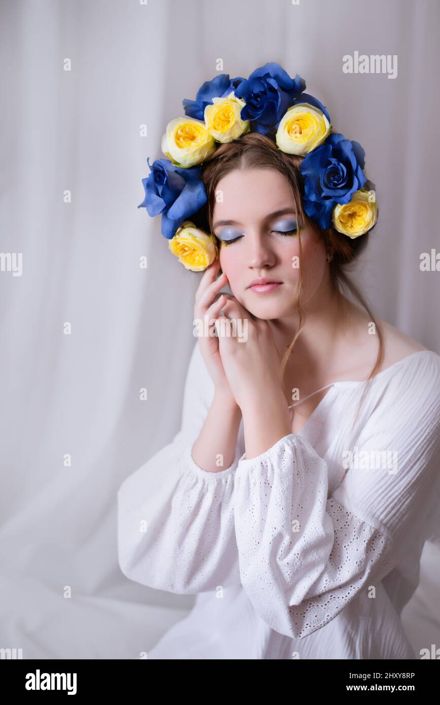 Belle femme ukrainienne dans une couronne blanche et fleurie. Symbole du drapeau bleu jaune