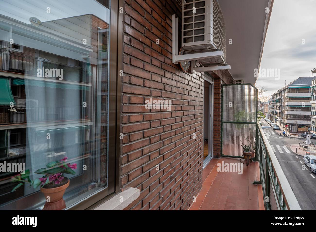 Appartement de vacances terrasse avec sol en argile et briques brunes donnant sur une rue urbaine, fenêtres brunes en aluminium et condenseur de climatisation Banque D'Images