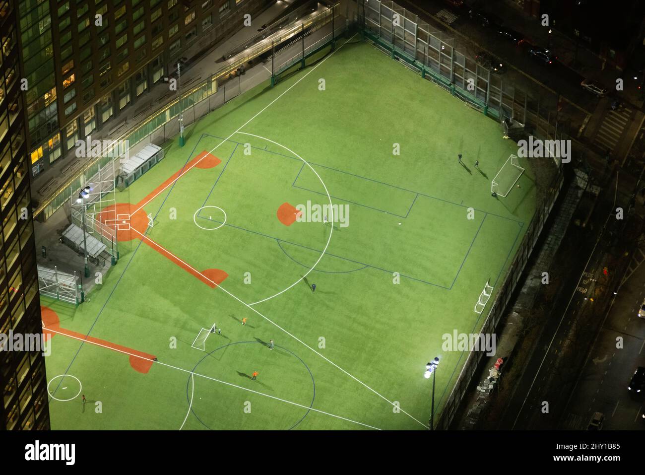 Depuis le dessus du terrain de baseball vert avec des lignes blanches situé près du bâtiment moderne la nuit dans la ville de New York Banque D'Images