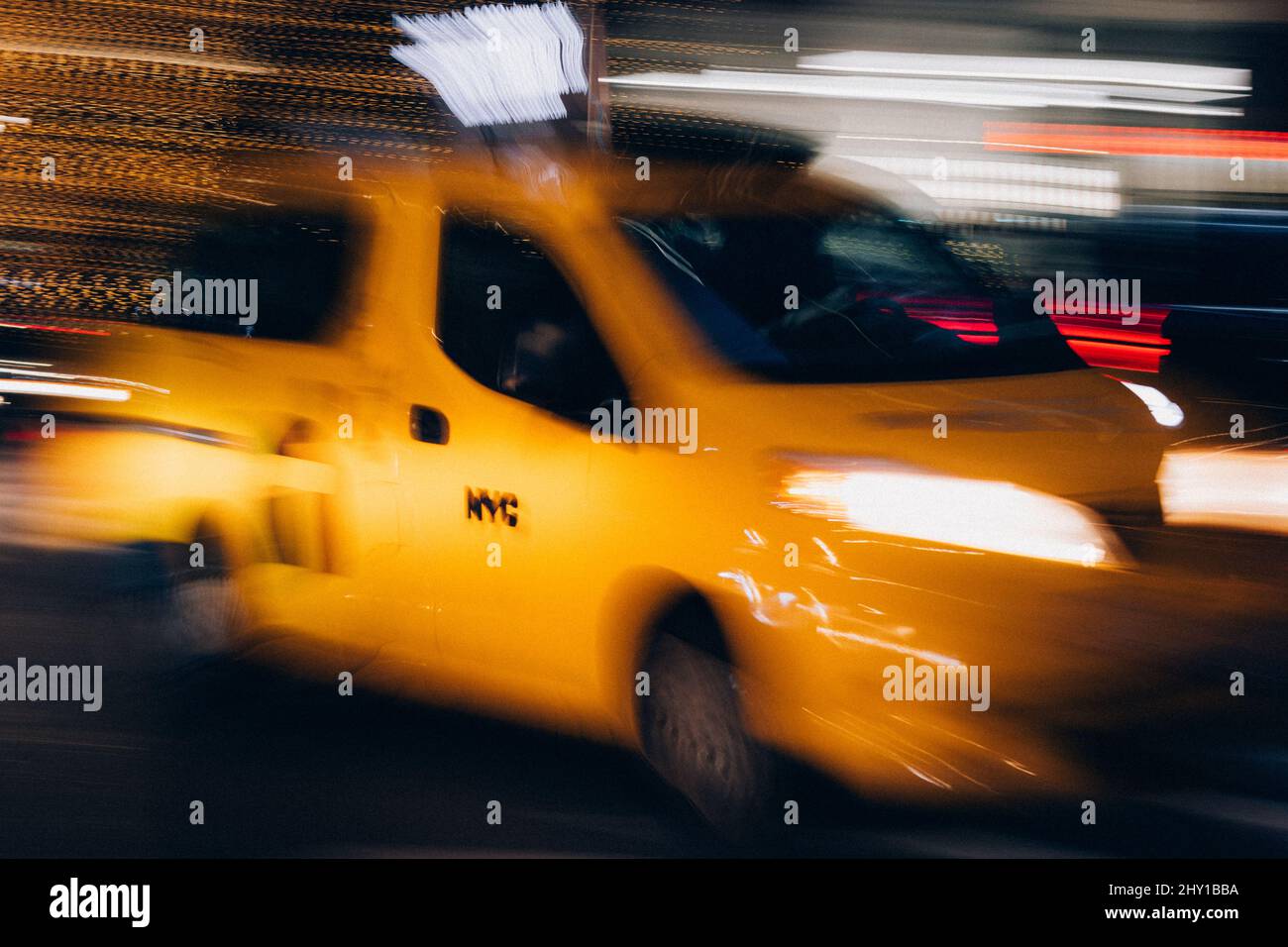 Voiture de taxi jaune floue avec des phares lumineux conduite en mouvement dans les rues sombres de la ville de New York la nuit Banque D'Images