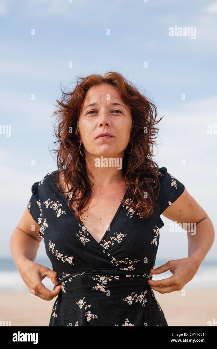 Une femme tranquille dans une chambre à l'écart avec le sourire tout en se tenant sur la côte sablonneuse près de la mer dans une station tropicale le jour de l'été Banque D'Images