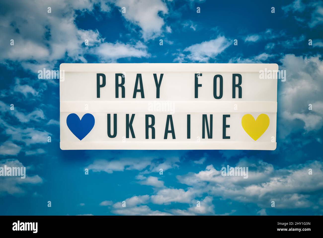 PRIEZ POUR L'UKRAINE écrit dans une visionneuse sur les nuages ciel arrière-plan. Ukraine concept de crise Banque D'Images