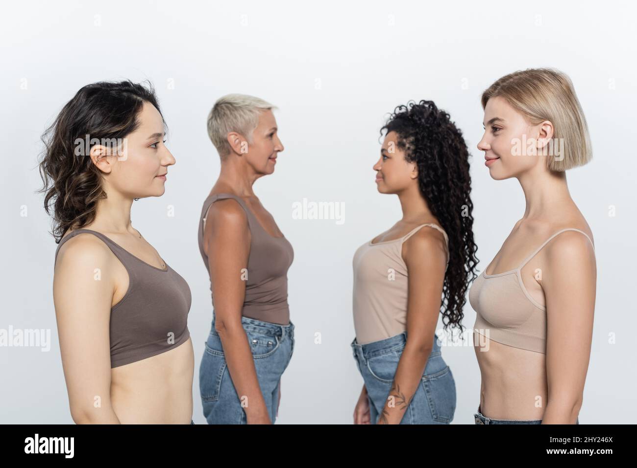 Vue latérale des femmes multiethniques se regardant les unes les autres isolées sur image grise Banque D'Images