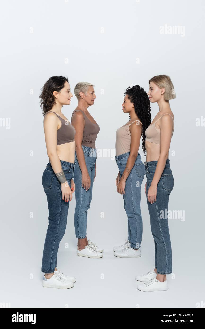 Vue latérale des femmes interraciales regardant l'une l'autre sur fond gris, image de stock Banque D'Images