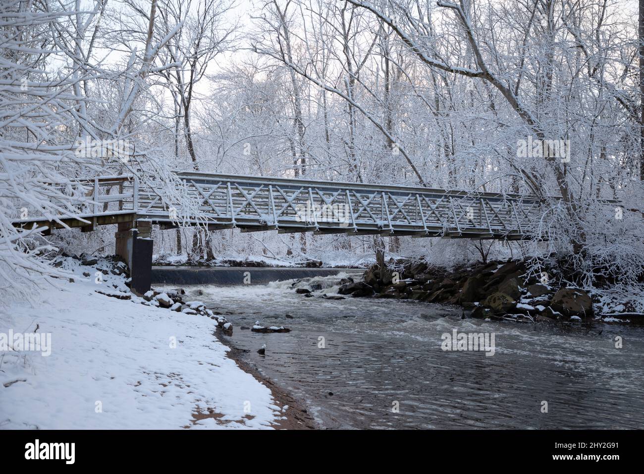 Pont couvert de neige au-dessus de la rivière dans les bois Banque D'Images