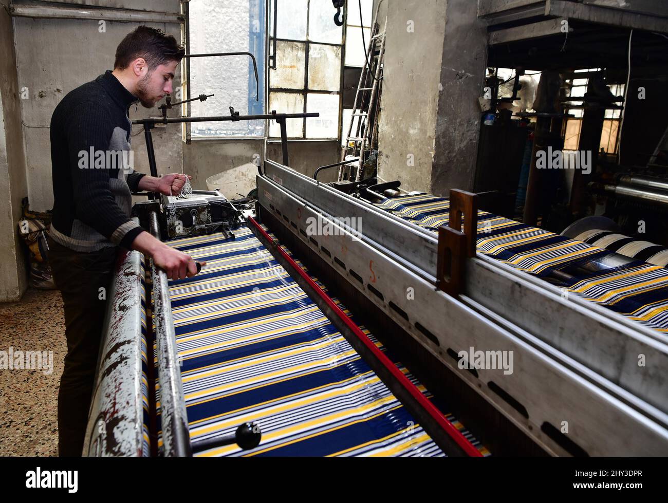 Alep. 7th mars 2022. Un homme syrien travaille dans un atelier textile à la ville industrielle d'Al-Qatirji, dans la ville d'Alep, au nord de la Syrie, le 7 mars 2022. Alors que la crise syrienne entre dans ses 12th années, les sanctions américaines et occidentales restent un obstacle majeur au retour d'une vie normale dans le pays. Les sanctions économiques, en particulier, ont paralysé la plupart des usines du pays déchiré par la guerre. Crédit: Ammar Safarjalani/Xinhua/Alamy Live News Banque D'Images