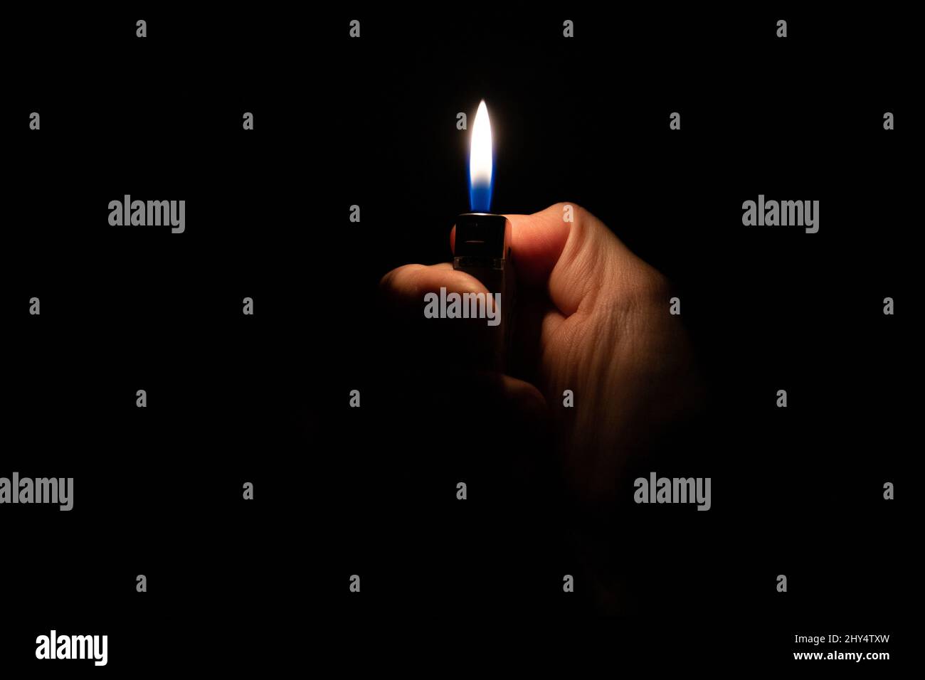 Main tenant un briquet sur fond noir Banque D'Images