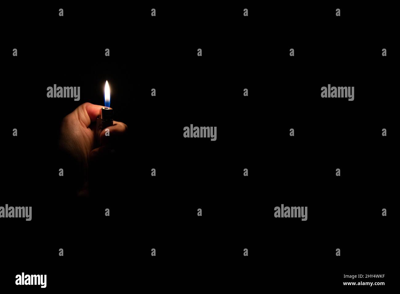 Main tenant un briquet sur fond noir Banque D'Images