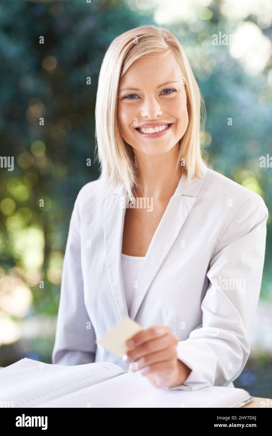 Laissez-moi vous donner ma carte. Portrait d'une jeune femme heureuse souriant à l'appareil photo tout en tenant une carte de visite. Banque D'Images