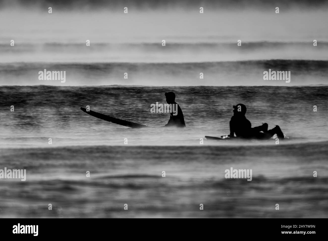 Niveaux de gris des surfeurs dans la mer Banque D'Images