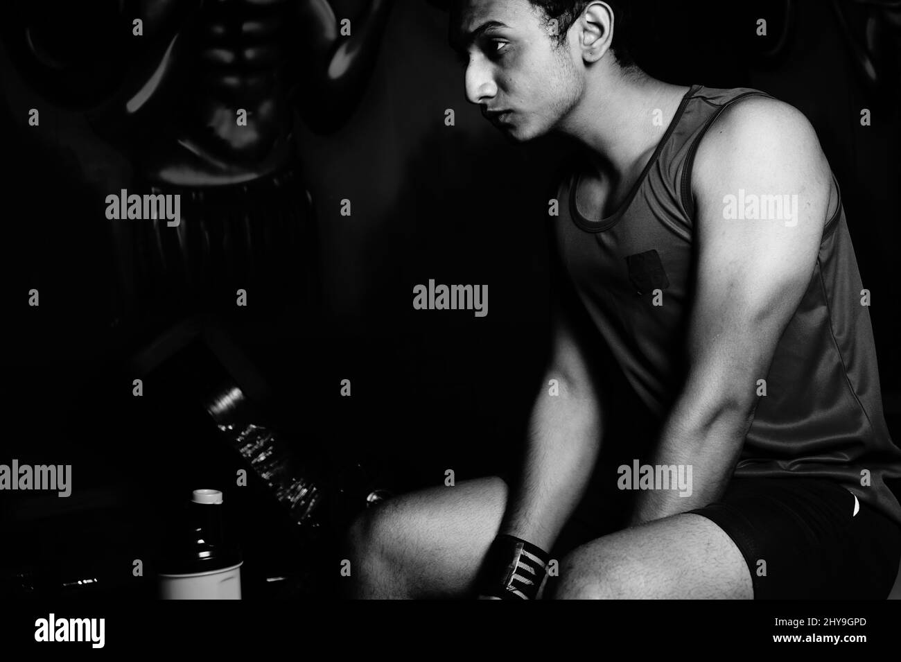 Échelle de gris d'un jeune homme indien faisant de l'exercice dans une salle de gym Banque D'Images