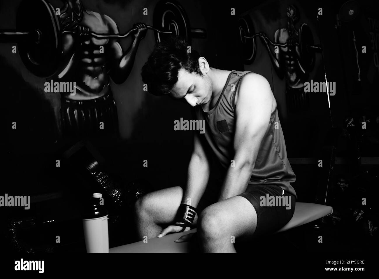 Échelle de gris d'un jeune homme indien faisant de l'exercice dans une salle de gym Banque D'Images