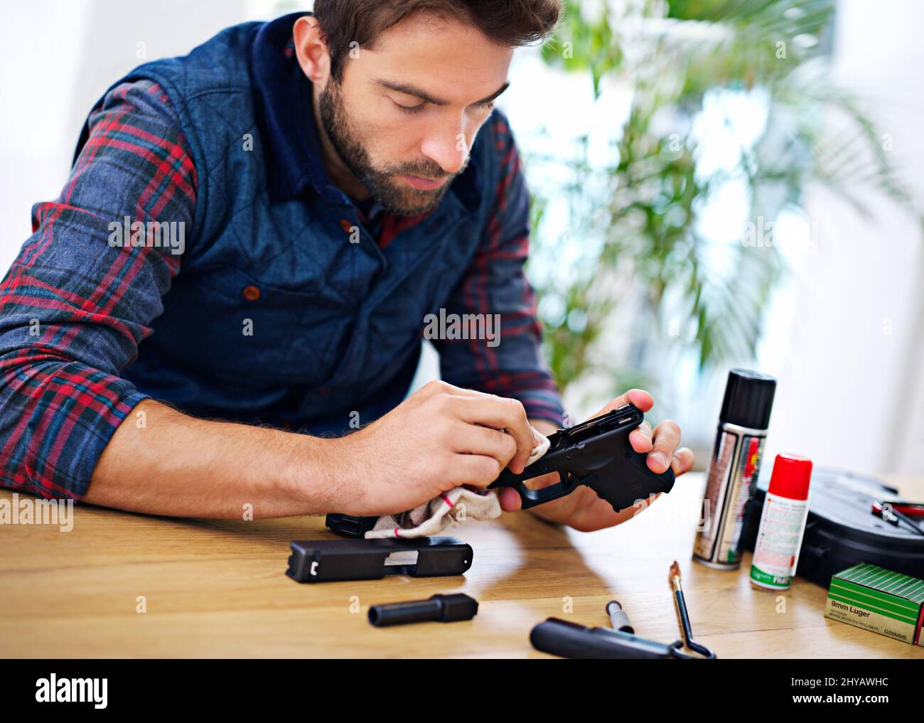 Un entretien régulier est essentiel pour chaque propriétaire de pistolet. Un jeune homme nettoyant son fusil. Banque D'Images