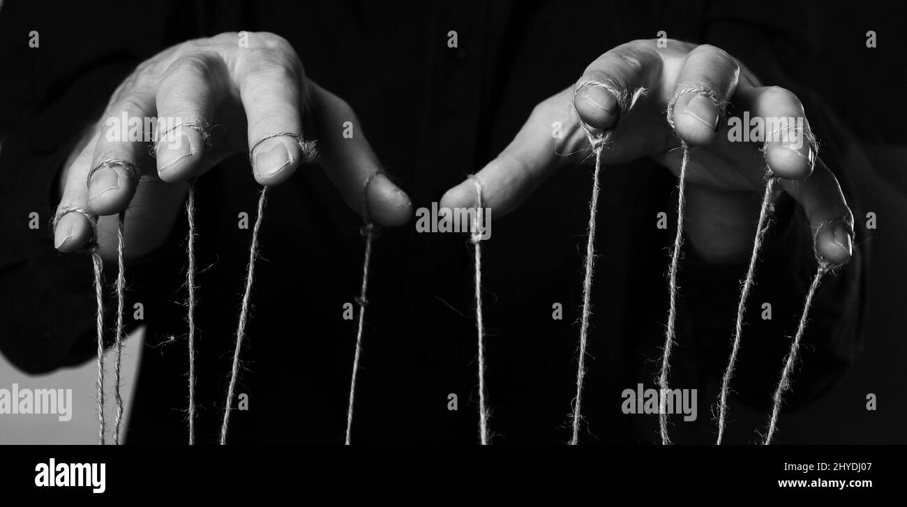 Influence et manipulation. Mains d'homme avec des cordes sur les doigts pour le contrôle, l'abus. Photo de haute qualité Banque D'Images