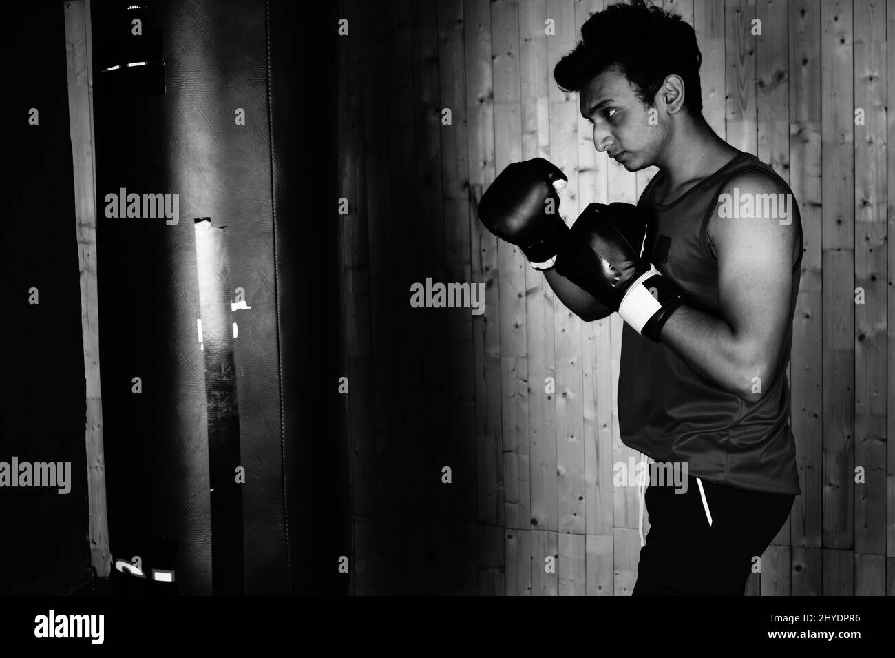 Gros plan d'un sportif masculin lors d'un entraînement de boxe en salle de sport sur une échelle de gris Banque D'Images