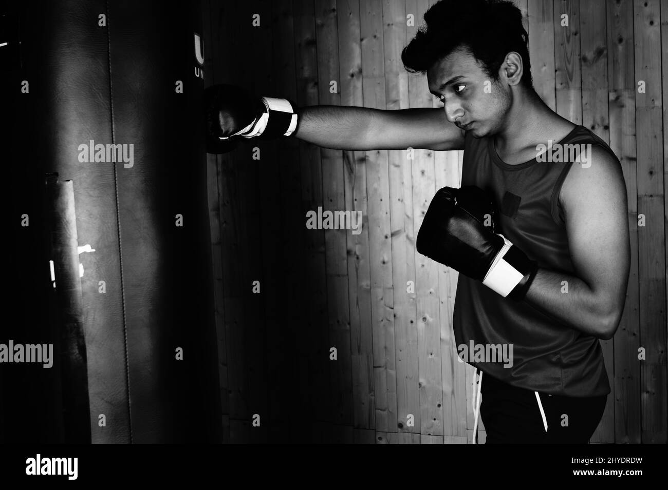 Gros plan d'un sportif masculin lors d'un entraînement de boxe en salle de sport sur une échelle de gris Banque D'Images