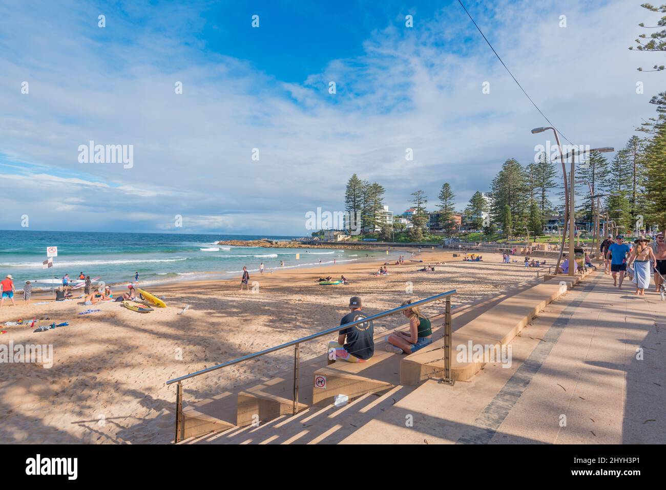 Les personnes qui nagent et se promènent le long de la promenade en fin d'après-midi en été à la plage de Dee Why à Sydney, Nouvelle-Galles du Sud, Australie Banque D'Images