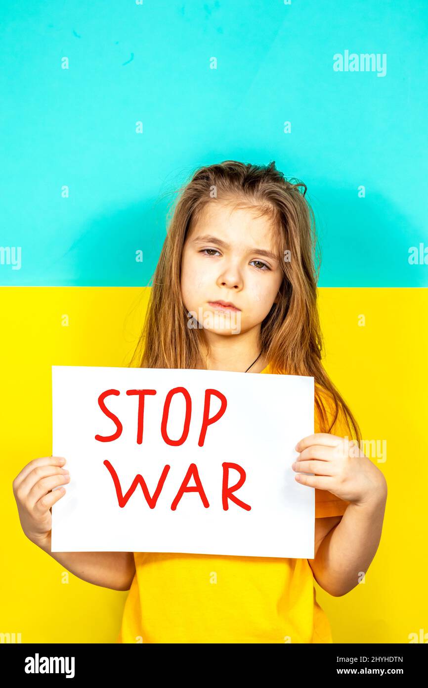 Le visage d'une fille qui pleure en gros plan. Une fille tient une AFFICHE D'ARRÊT dans ses mains contre le fond du drapeau ukrainien. Arrêter la guerre en Ukraine. Le Banque D'Images