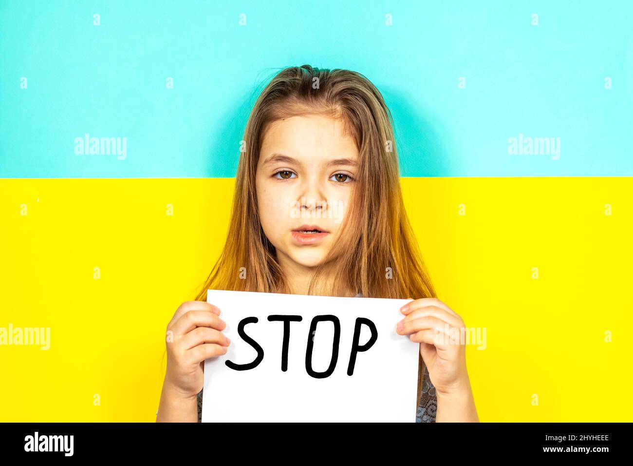 La fille tient une AFFICHE D'ARRÊT dans ses mains contre le fond du drapeau ukrainien. Arrêter la guerre en Ukraine. Le concept de paix en Ukraine Banque D'Images