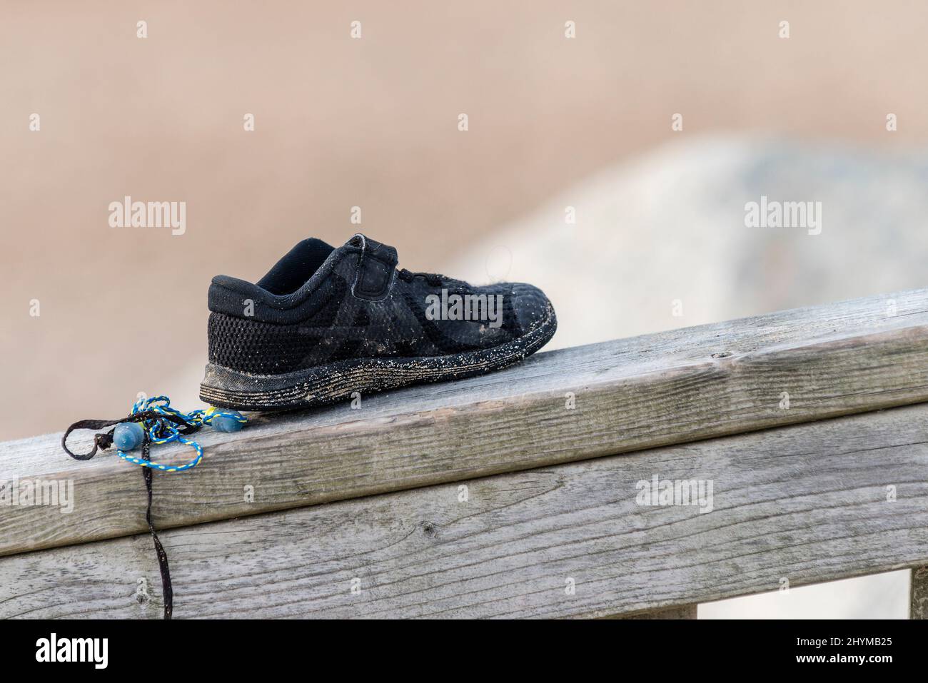 Une petite chaussure de plage laissée sur une rambarde en bois. Banque D'Images