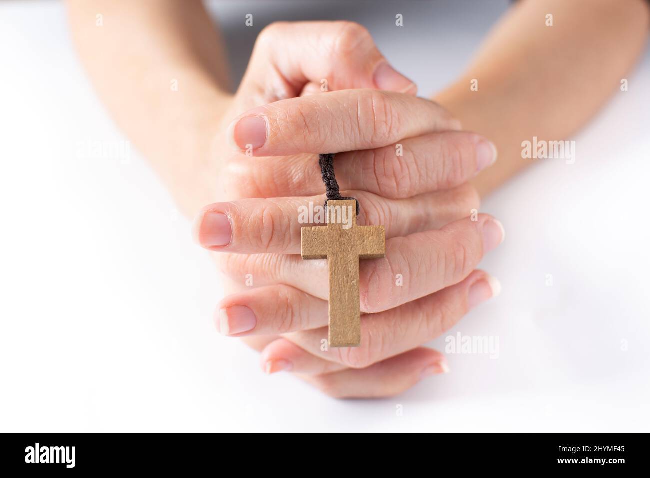 Femme priant avec la croix catholique Rosaire sur fond blanc Banque D'Images