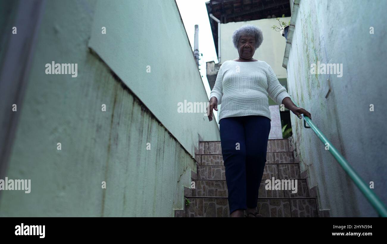 Une femme africaine descendant les escaliers ouvrant la porte de la maison et laissant la maison à la rue piétonne urbaine Banque D'Images