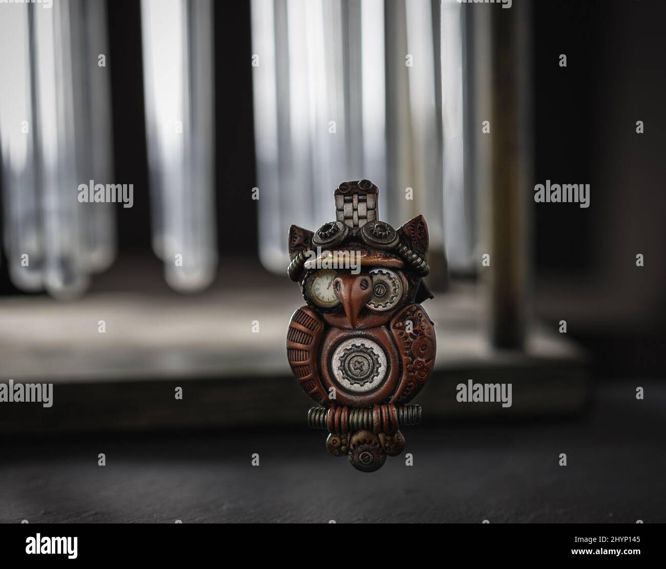 Gros plan d'une broche en céramique artisanale d'un hibou sur une surface en pierre sur un fond de flacons en verre Banque D'Images