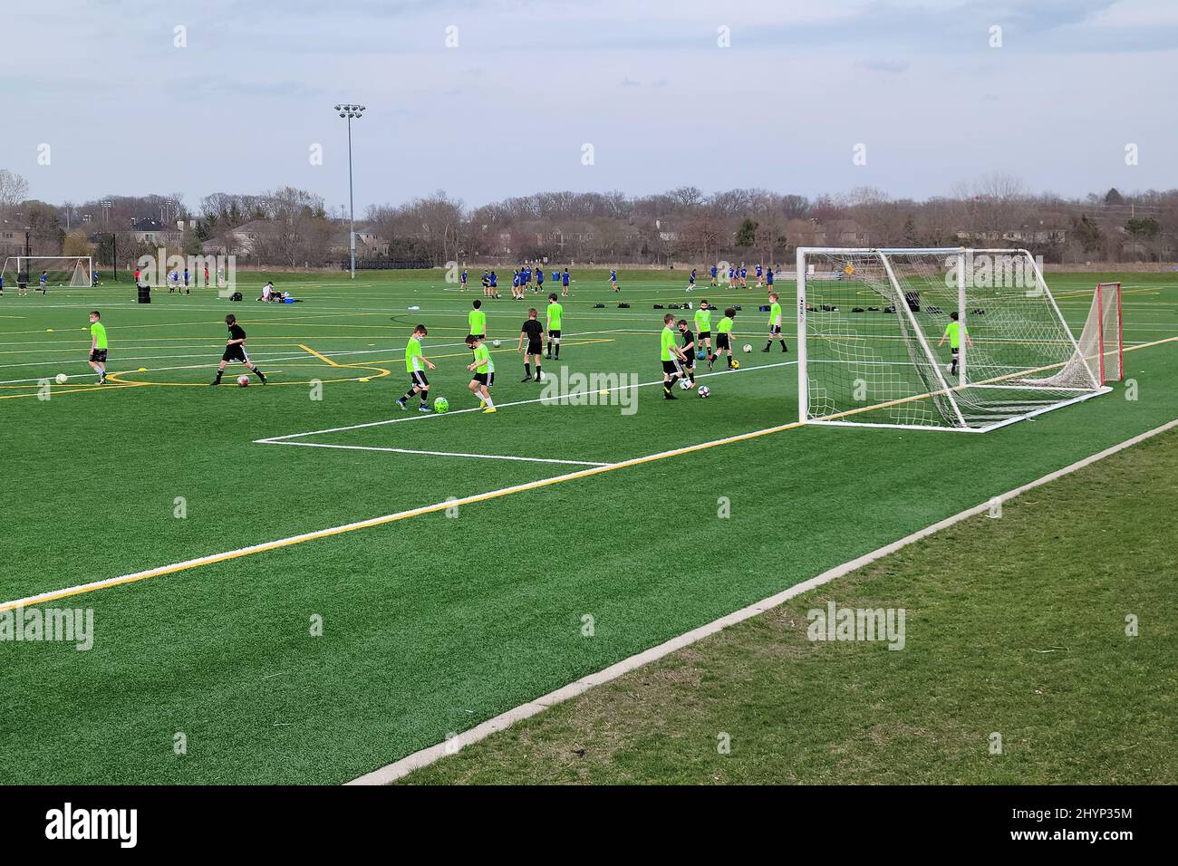 Des garçons pratiquant le football sur un terrain de balle polyvalent au début du printemps dans un parc local. Banque D'Images