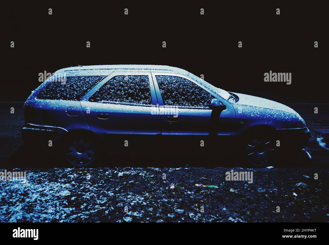 Scène nocturne de rue pendant l'hiver, voiture dans l'obscurité avec quelques chutes de neige. Banque D'Images