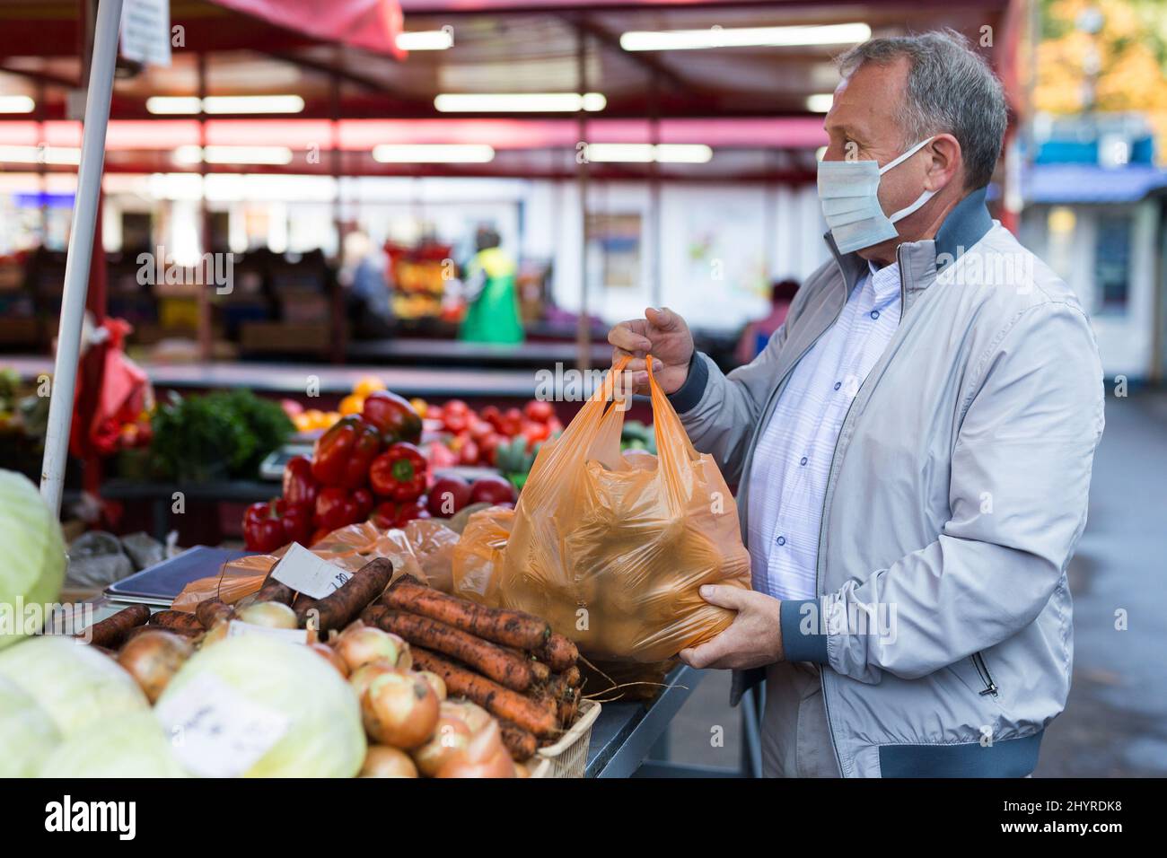 Homme d'âge moyen en masque achetant des pommes de terre Banque D'Images