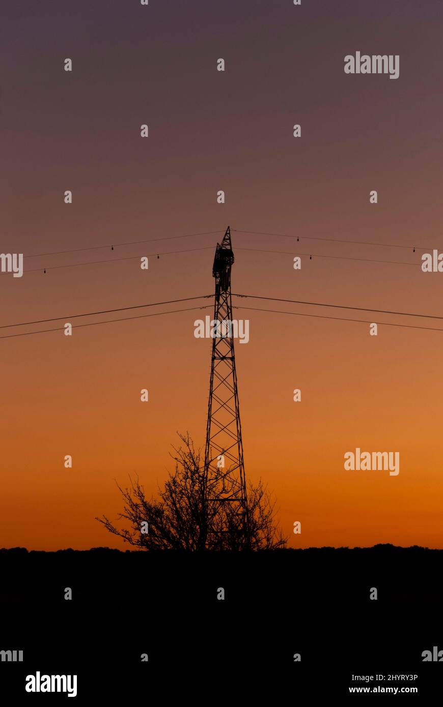 Tour électrique au coucher du soleil avec ciel orange, prix de l'électricité Banque D'Images