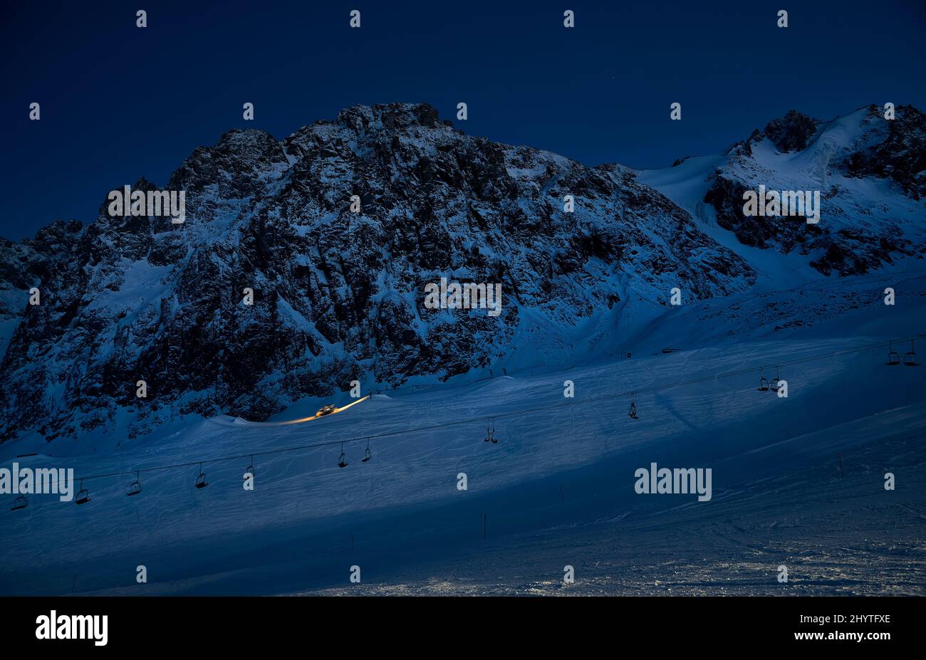 Silhouette de ratrack moderne de chat de neige avec lumière LED préparant la piste de ski au parc de neige nocturne avec ciel étoilé à la station de ski de Shymbulak Almaty, Kazakhstan Banque D'Images
