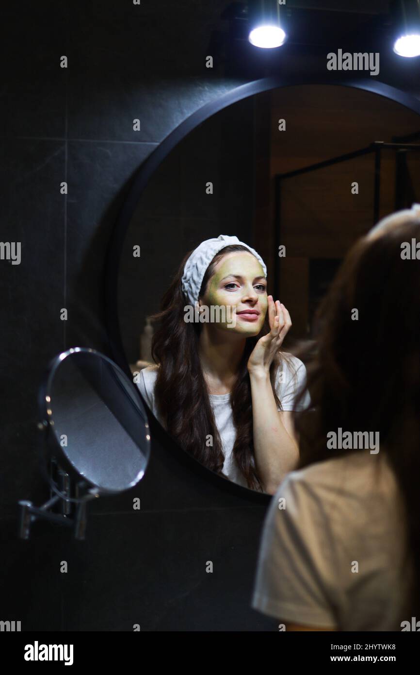 Fille prenant soin de teint huileux en utilisant le masque d'argile vert. Femme dans le bandeau Banque D'Images