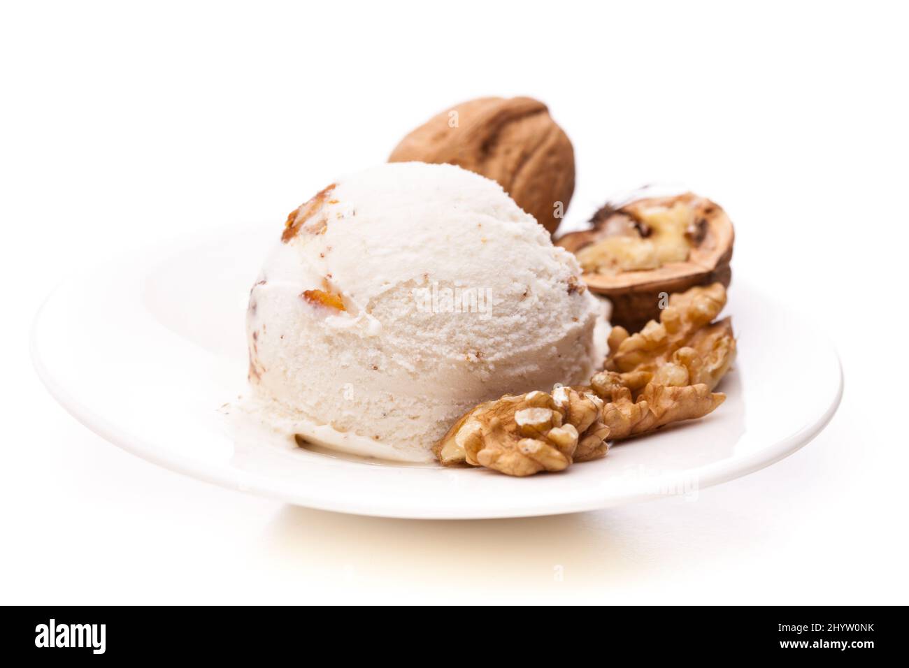 une seule cuillère à glace en noyer avec des noix sur une assiette sur fond blanc Banque D'Images