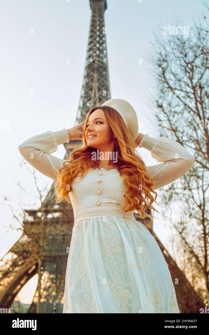 Une fille sur le fond de la Tour Eiffel à Paris dans un béret et une robe aux cheveux courbés, un voyage romantique. Femme riant et regardant loin. Banque D'Images