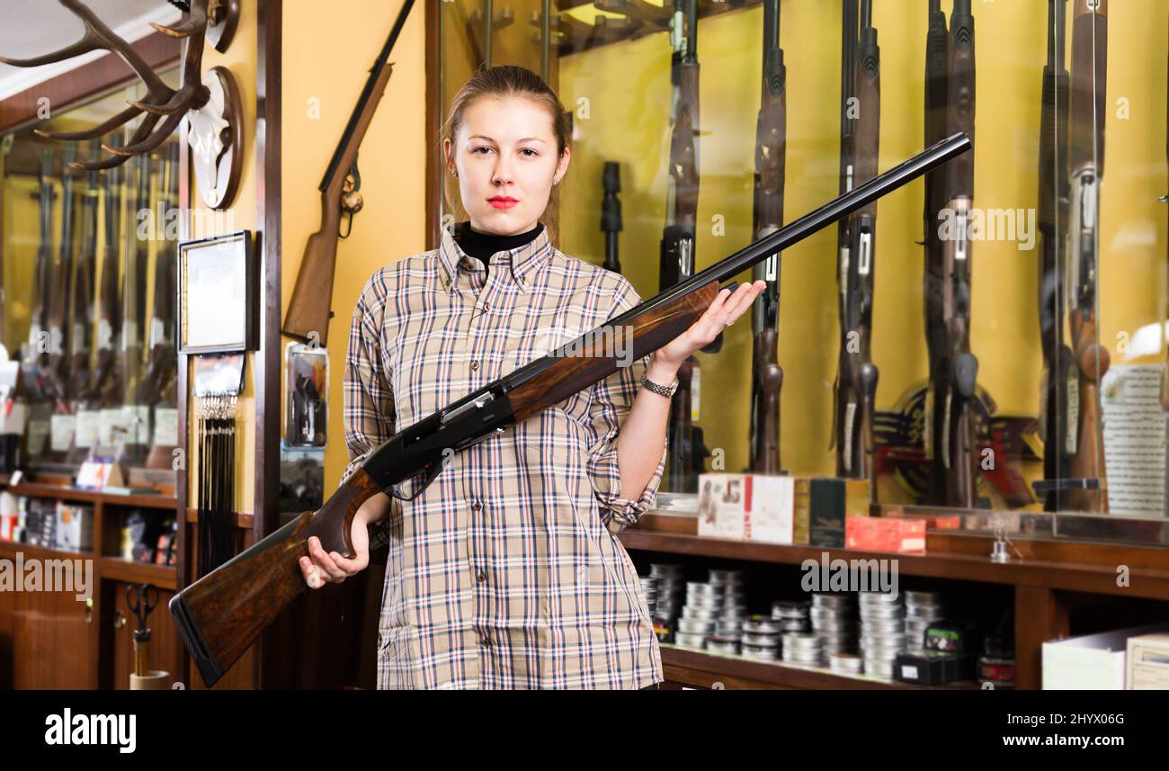 Femme souriante dans un magasin de chasse avec carabine Banque D'Images