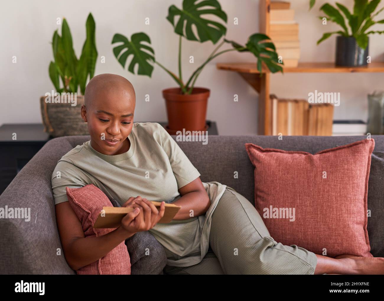 Une jeune femme lit un roman à la maison sur le canapé Banque D'Images